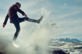 Man kicks snow through the air